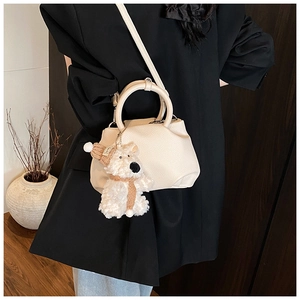 Detail of cream pleated leather bucket bag with cute teddy bear charm on black blazer