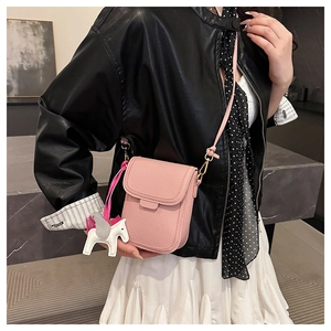 Détail d'un sac de téléphone rose en cuir grainé avec un pendentif cheval blanc décoratif