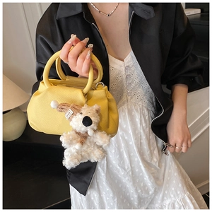 Detail of yellow pleated bucket bag with lychee texture and cute plush bear charm