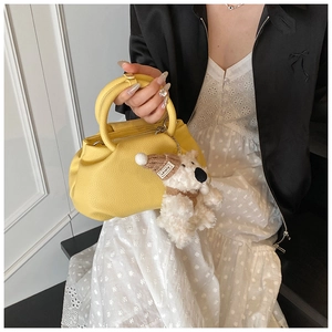 Close-up of bright yellow pleated leather bucket bag with a cute white teddy bear charm