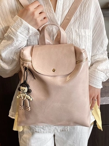Chic light pink leather backpack for women featuring a top flap and cute cartoon pendant