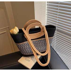 Detail of hand-woven tote bag with dual handles and black-pink contrast knit texture