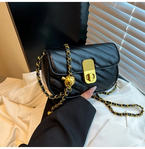 Détail du sac bandoulière matelassé noir avec coutures en V et chaîne dorée à boule
