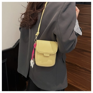 Détail d'un mini sac bandoulière jaune en cuir grainé avec un petit pendentif éléphant