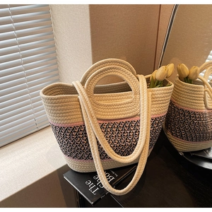 Detail of hand-woven straw tote with pink pattern, round handles and long straps