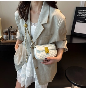 Détail du sac bandoulière blanc matelassé avec chaîne dorée et boule réglable