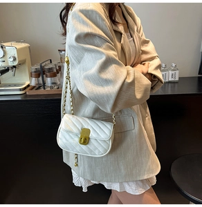 Détail du sac bandoulière matelassé blanc avec fermoir doré et bandoulière en chaîne