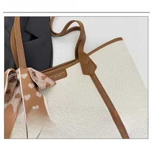 Détail d'un sac cabas tissé avec anses en cuir marron et foulard à cœurs