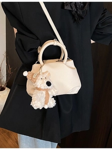 Chic cream-colored pebbled leather bucket bag with cute plush puppy charm on model