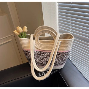 Detail of woven tote bag showing dual-handle design and pink-black patterned base