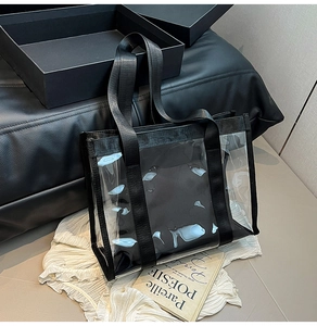 Detail view of transparent PVC tote bag with black nylon handles and reinforced seams