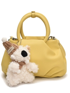 Yellow pleated leather bucket handbag with a cute white plush bear charm on white background