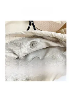 Detail of round magnetic closure and herringbone lining on the cream drawstring backpack