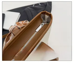 Détail de la fermeture à glissière argentée et bordure en cuir marron du sac fourre-tout