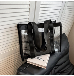 Détail du sac cabas en PVC transparent avec sangles en toile noire sur un canapé en cuir