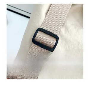 Macro detail of adjustable shoulder strap with black buckle on beige drawstring backpack