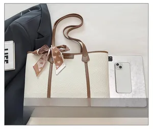 Détail d'un sac cabas tissé avec bordure en cuir marron et foulard en soie pour le travail