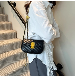 Détail du sac bandoulière noir matelassé avec fermoir rotatif doré et bandoulière chaîne