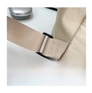 Detail of reinforced strap stitching and durable black plastic buckle on khaki backpack