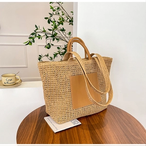 Close-up of a woven straw tote bag with brown leather handles on a cafe table