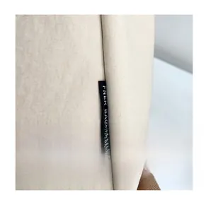 Detailed macro view of the textured canvas fabric and FNER BAG logo label on a beige backpack