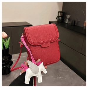Détail du sac de téléphone rouge texture litchi avec breloque pégase à pompon