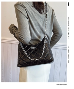 Détail du sac à bandoulière noir matelassé avec chaîne argentée et fermoir métallique