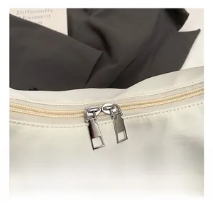 Detail of premium dual silver metal zippers on white nylon crossbody dumpling bag