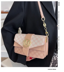 Détail d'un sac à bandoulière rose et beige avec motif M et boucle en métal doré