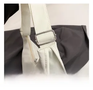 Detail of adjustable shoulder strap with silver buckle on beige PU leather crossbody bag