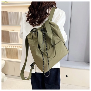 Model wearing army green multipurpose drawstring backpack showing size and fit in soft light