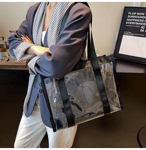Détail d'un sac cabas transparent en PVC avec bandoulière noire porté par un mannequin