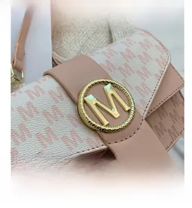 Détail d'un sac à main en cuir rose avec tissu jacquard à motif M et boucle dorée
