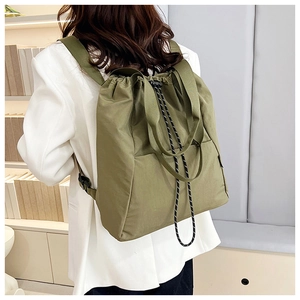 Army green drawstring backpack detail showing buckled side straps and woven handle