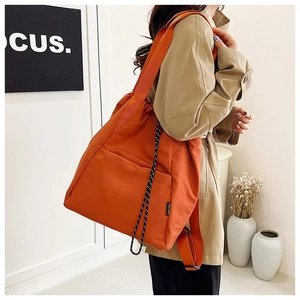 Detail view of orange canvas tote bag with woven rope accents and wide shoulder strap