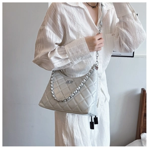 Gros plan d'un sac bandoulière matelassé blanc avec chaîne argentée sur un modèle