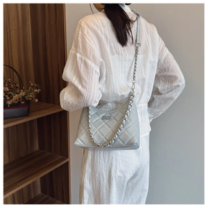 Détail du sac en cuir matelassé gris clair avec chaîne argentée et fermoir rotatif