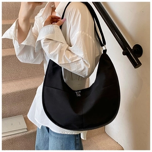 Close-up of minimalist black nylon crescent hobo bag with wide shoulder strap on model