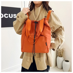 Detail of vibrant orange drawstring backpack featuring durable nylon fabric and side tag