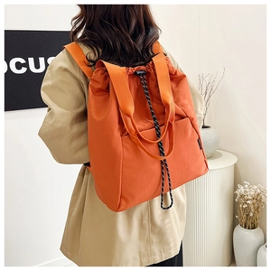 Detail view of large orange drawstring backpack with side pockets and top handle