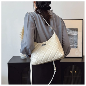 Détail du sac matelassé crème avec bandoulière chaîne argentée et fermoir rotatif
