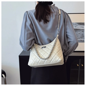 Détail d'un sac matelassé à chaîne avec fermoir argenté porté par un mannequin