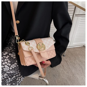 Détail du sac bandoulière rose à monogramme M porté par un mannequin en tenue décontractée