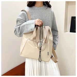 Detail of drawstring closure and nylon straps on a beige multi-way fashion backpack