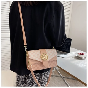Détail d'un sac à bandoulière crème et rose avec motif M et boucle en métal doré élégant