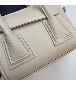 Detailed close-up of premium lychee texture leather and precise stitching on beige handbag