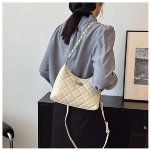 Détail du sac matelassé beige avec fermoir rotatif argenté et bandoulière en cuir