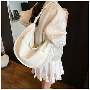 Detail view of a white crescent moon shoulder bag with soft matte leather texture