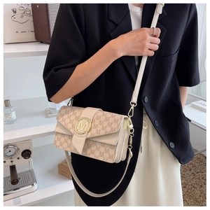 Sac bandoulière beige chic avec motif monogramme porté par un mannequin en intérieur élégant