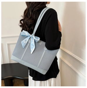 Détail d'un sac cabas tissé bleu clair avec foulard en soie et anses en similicuir